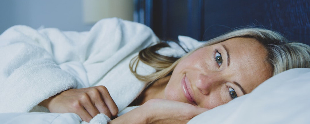 Woman with head on pillow showing benefit of good night's sleep.