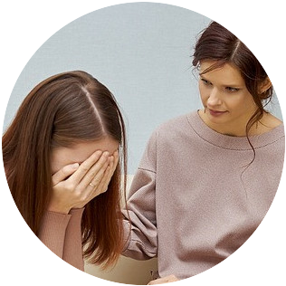 Woman with hands covering face speaking to woman friend