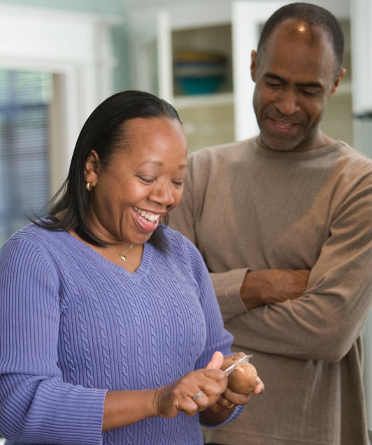 middle age man and woman preparing dinner while smiling